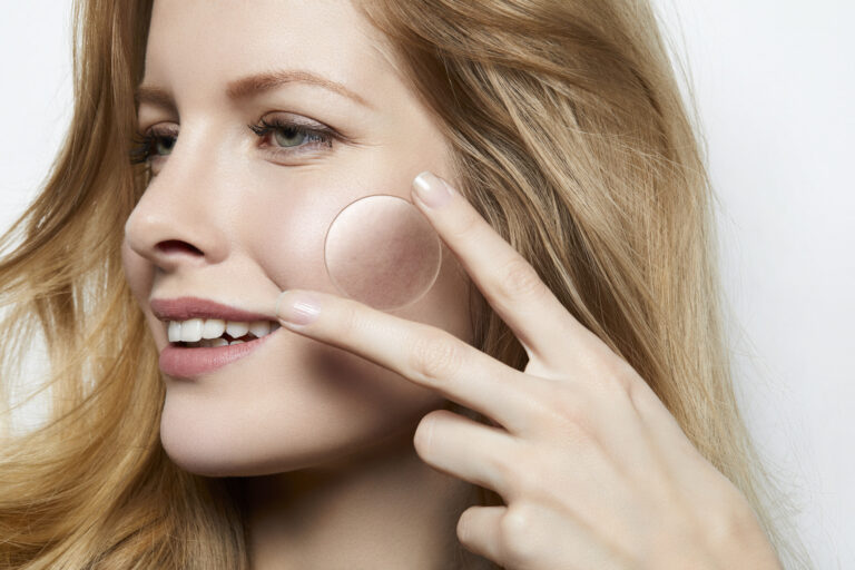 beautiful woman with flawless skin holding a magnifying glass over a part of skin with acne